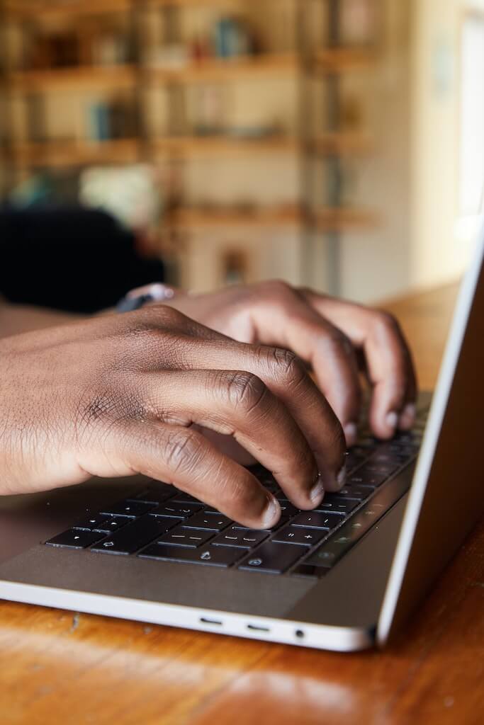 Cropped image of hands of man typing on laptop