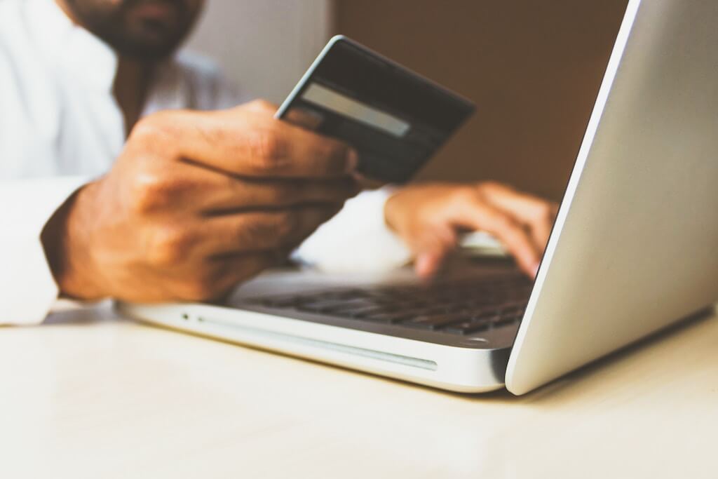 Close up of man using debit card to pay online